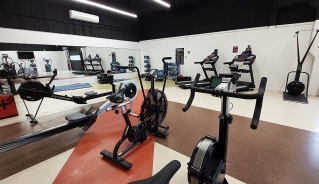 Bikes, rowers and treadmills stationed alongside walls with a mirror across the back wall.