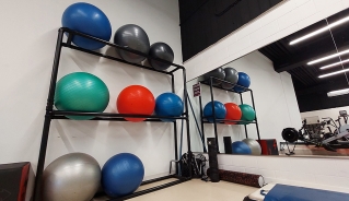 Inflatable fitness balls in three rows on a vertical rack in front of a mirror.