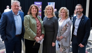 Five advancement dinner guests standing together and smiling at the camera.
