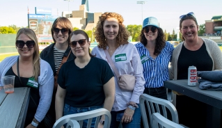 Six Assiniboine College Alumni standing together at the Goldeyes game in Winnipeg.