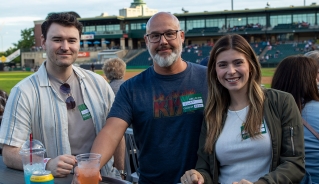 Three Assiniboine College Alumni standing together at the Goldeyes game in Winnipeg.
