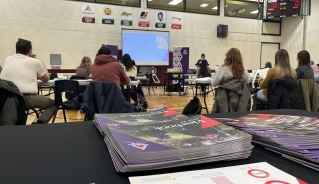Photo of the publications table with a crowd of counsellors listening to a presentation in the background.