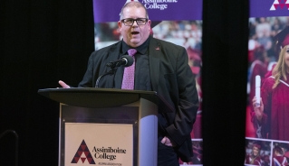 Mark Frison, Assiniboine College president, speaking at a podium during the Alumni Advancement Dinner.