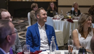 A table full of people smiling during the Alumni Advancement Dinner.