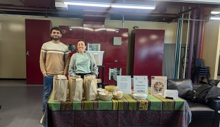 Two staff members, Mitesh and Cynthia, standing in front of a table with bags of food on it.
