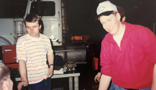 Warren Cowling standing with a group of people in a farm machinery shop.