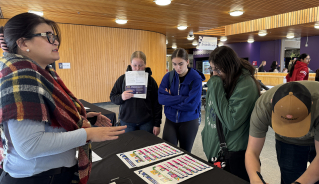Students gathered up around an information table at the cafeteria.