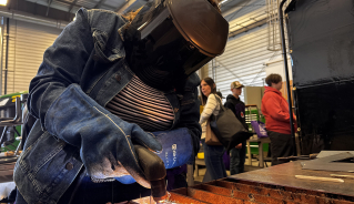 A student welding their name on a metal plate.