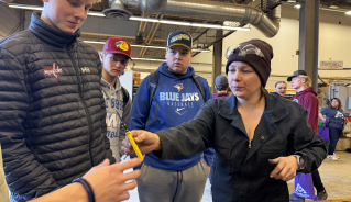 A volunteer handing wire strippers to a student.
