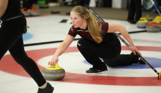 Women's curling team member throwing a yellow rock.