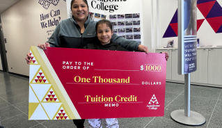Valeria H. holding a big red cheque.