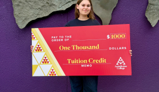 Viktoriia R. holding a big red cheque.