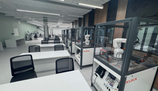 Mechatronics lab with a row of cases with robotic arms and desks placed next to them.