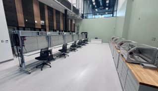 Mechatronics lab with a row of boards with cable slots, and a row of workbenches with other machines.