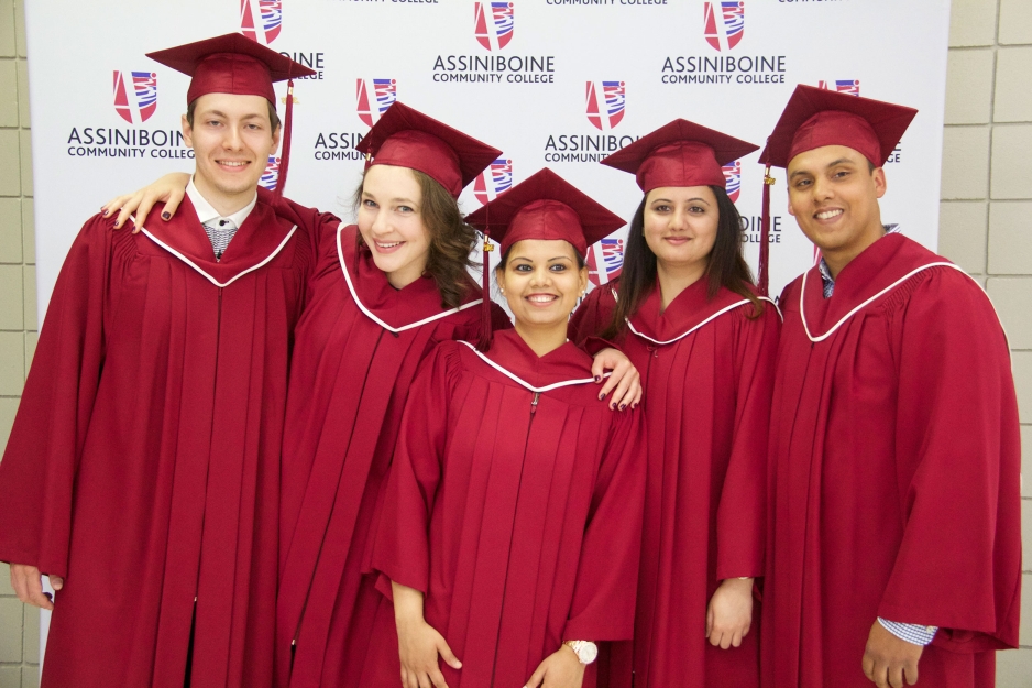 Five students in red graduation caps and gowns stand for a photo.