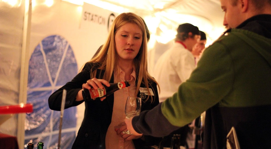 A student pours beer for a guest at Harvest on the Hill.