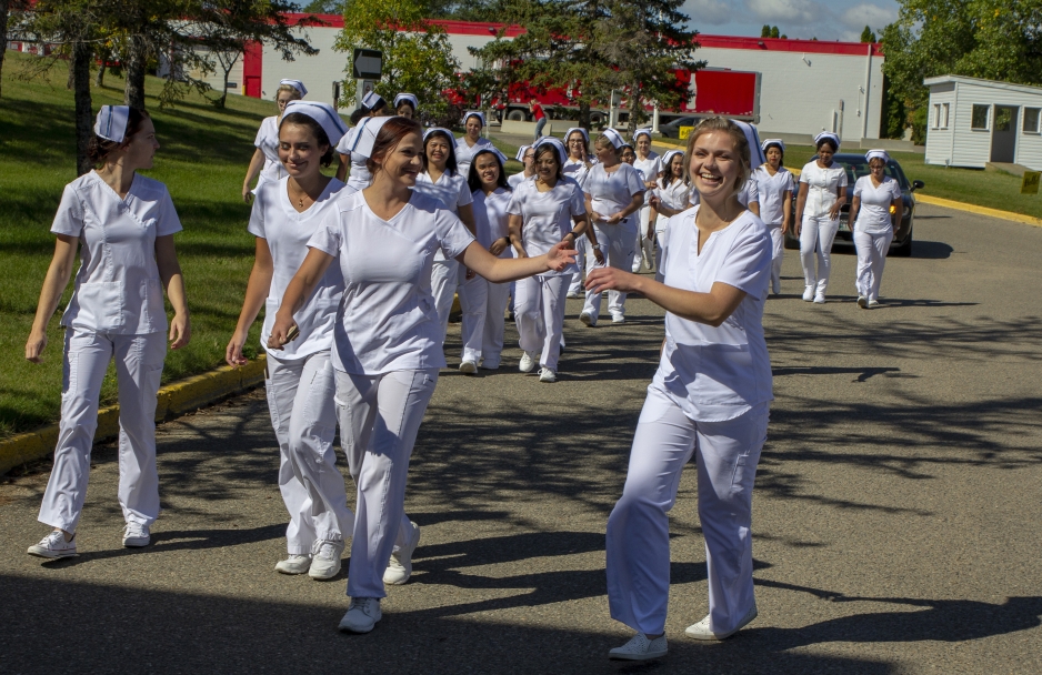 [front L to R:] Practical Nursing graduates Sabrina Dueck, Claudia Bryant and Morgan Wiebe walk with their classmates to the graduation ceremony.