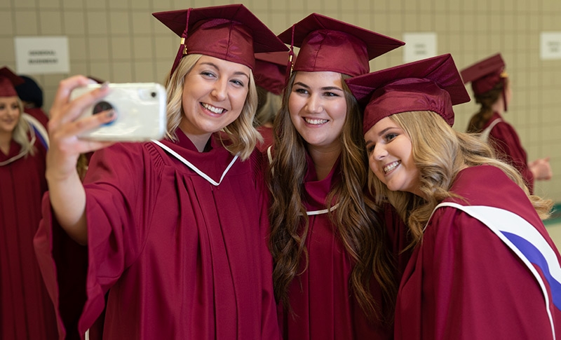 Graduates pose for a selfie.