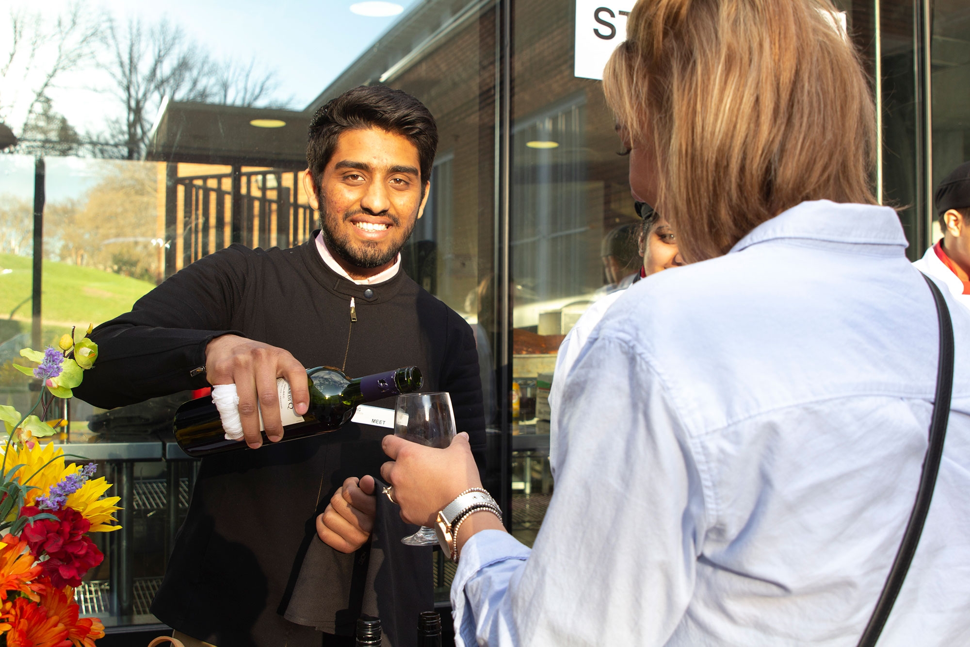 student pours wine to guest at MICA