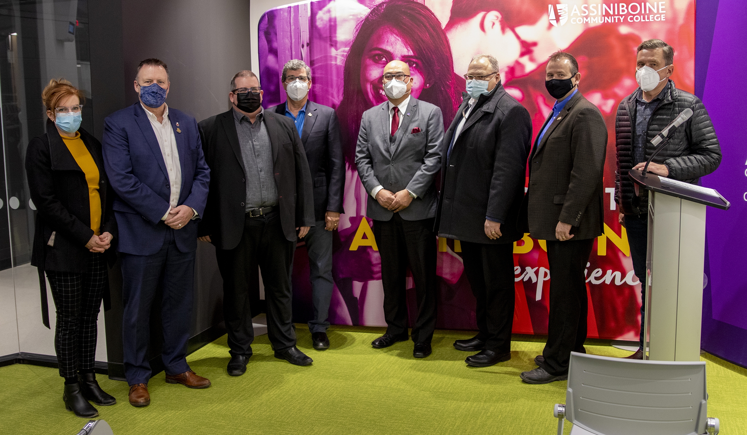 A group of eight individuals stand together, wearing masks.