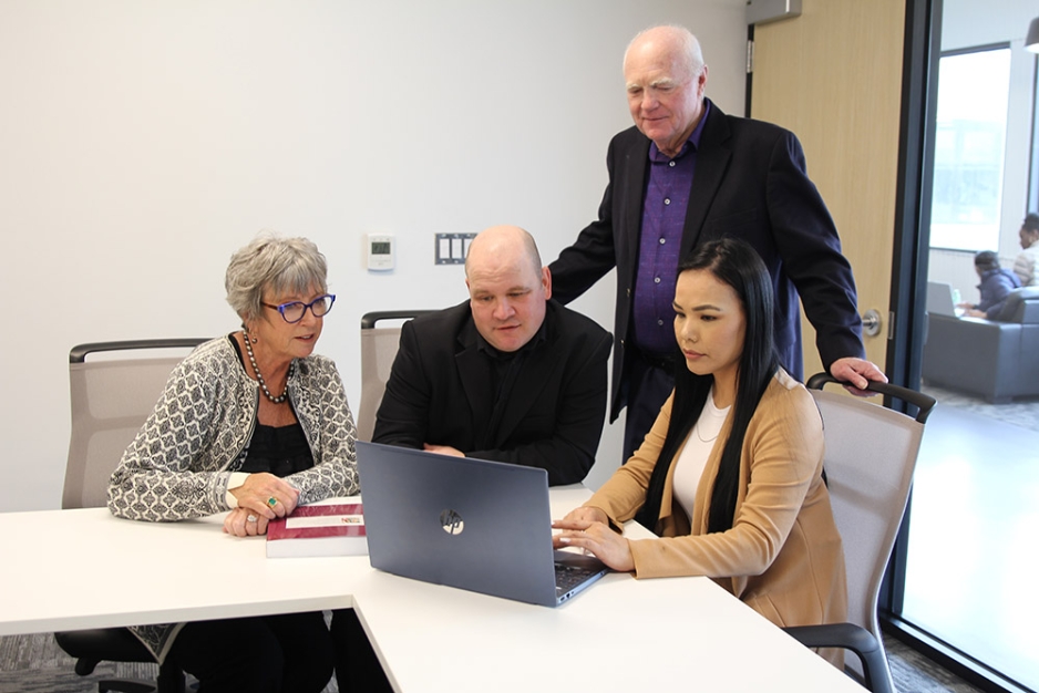 Gord and Diane Peters with two students in front of a laptop.