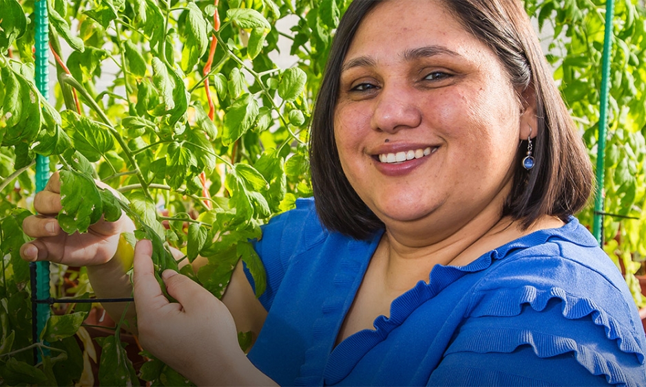 Dr Poonam Singh smiling at the camera while examining a plant.