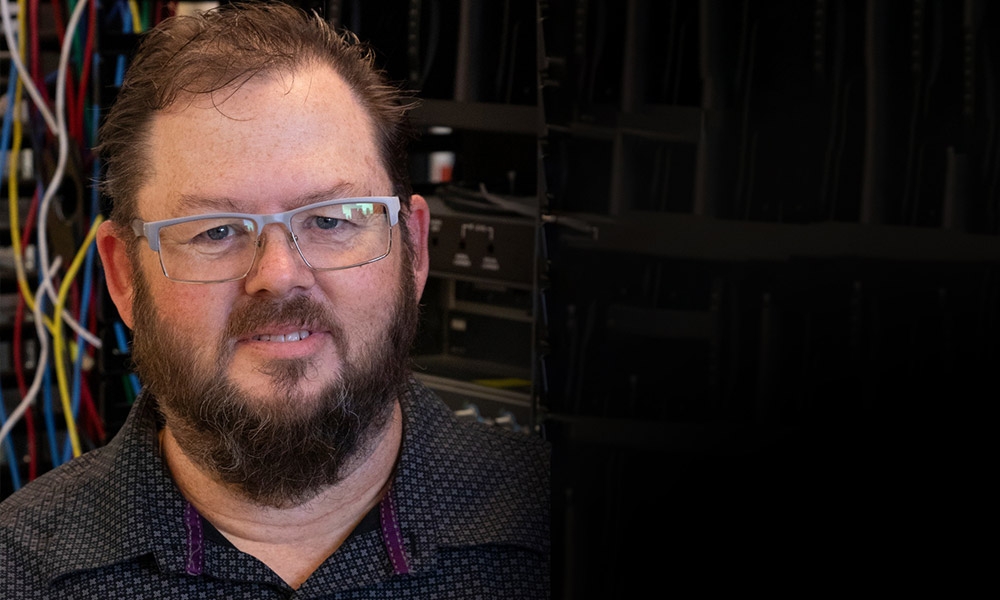 Grant Nicol standing in front of server racks and looking at the camera.