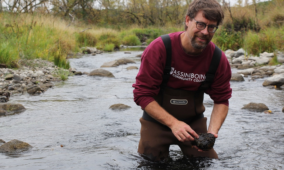 James Hood standing in a stream and smiling at the camera.