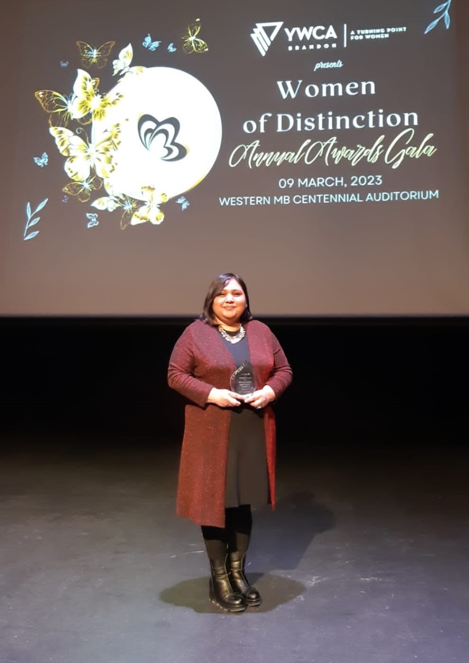 Dr. Poonam Singh standing on the WMCA stage, posing with a glass award during the "Women of Distinction" awards gala on March 9th, 2023.