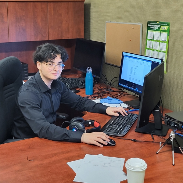 Haithem Bouabdel, Network Administrative Technology graduate, working at his desk at Compass Credit Union.