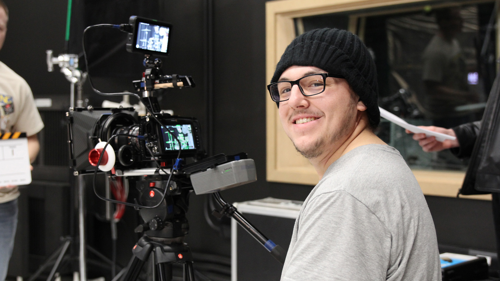 A media student sitting in front of a TV camera in a studio.