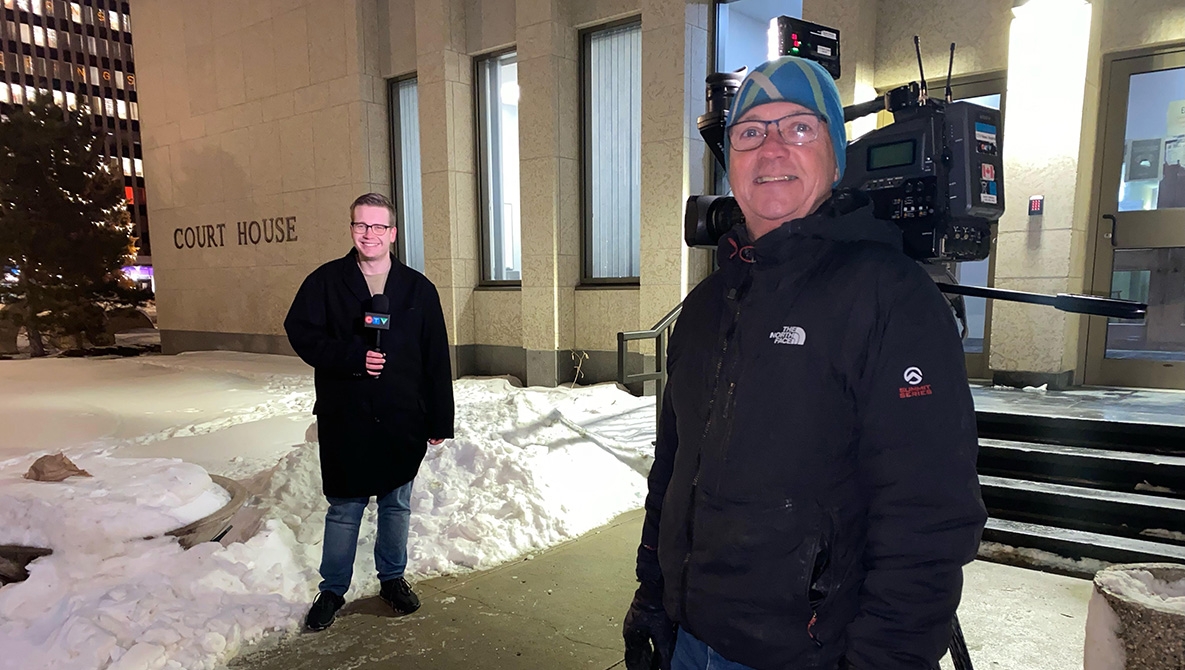 Cole Davenport and his coworker standing with a camera and microphone in front of a court house.
