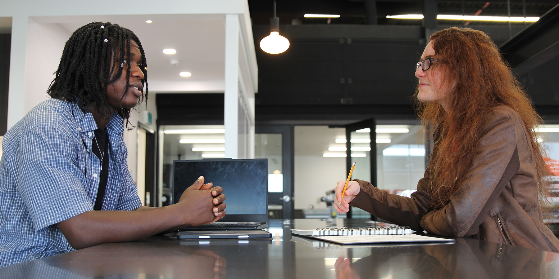 Two people sitting across from each other at a table in the Colab, discussing ideas.