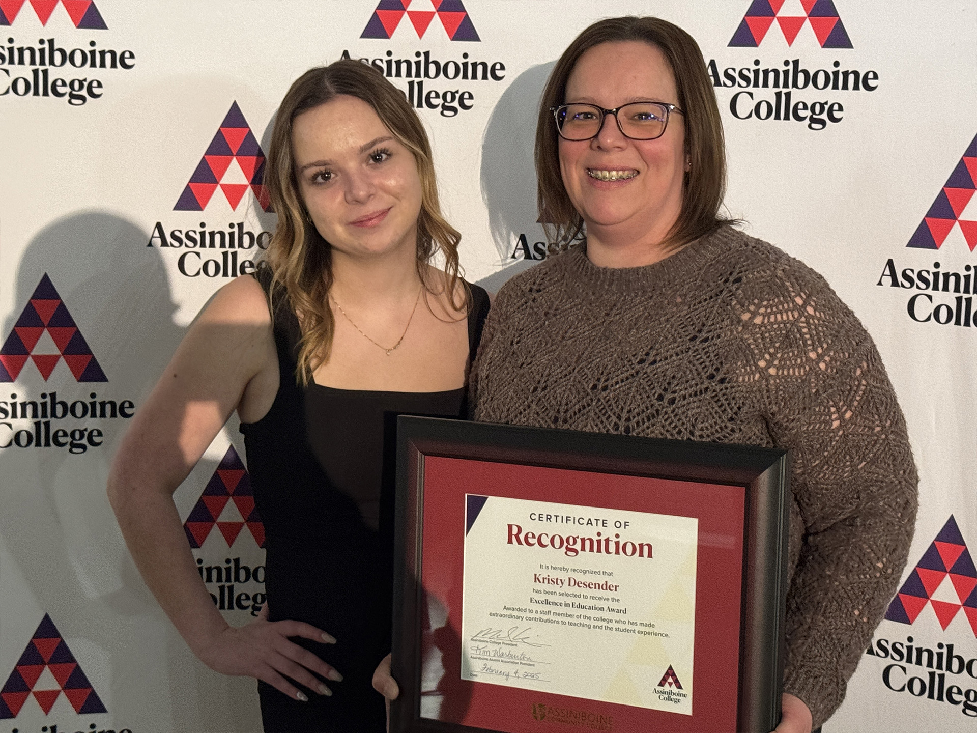 Kristy Desender posing with another person, holding her Alumni Awards certificate.