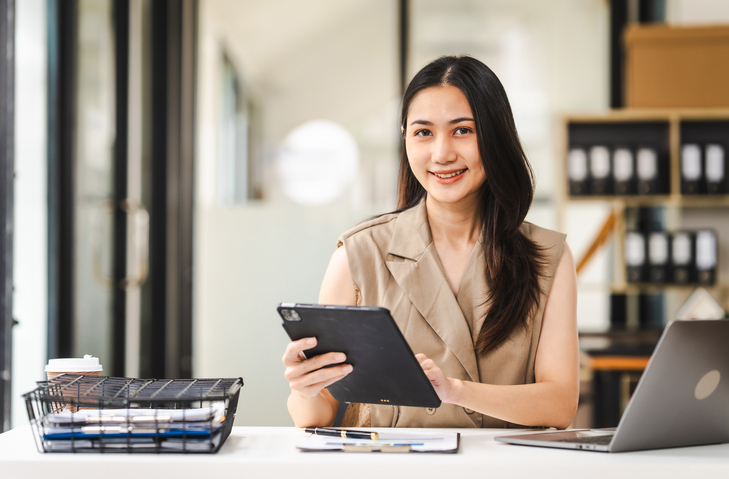 female smiling at camera while on iPad