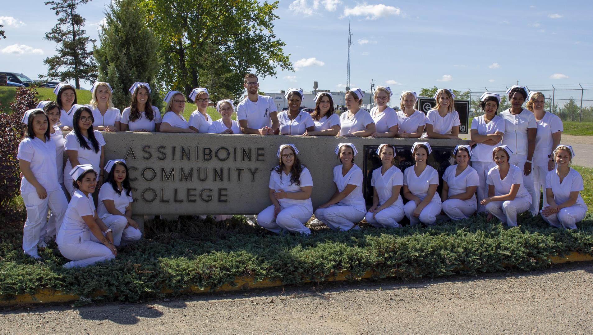 Nursing Graduates in front of college sign outdoors.