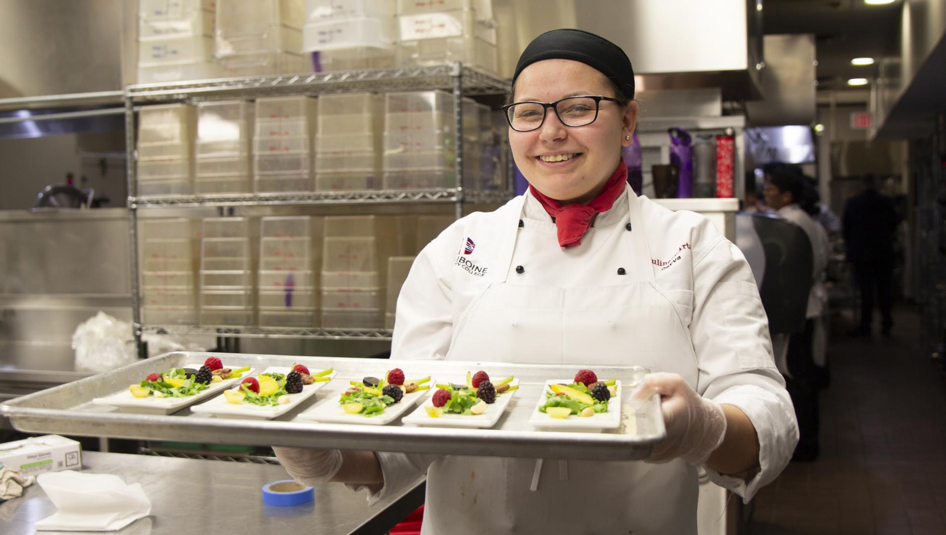 Culinary Arts student holding a tray of desserts