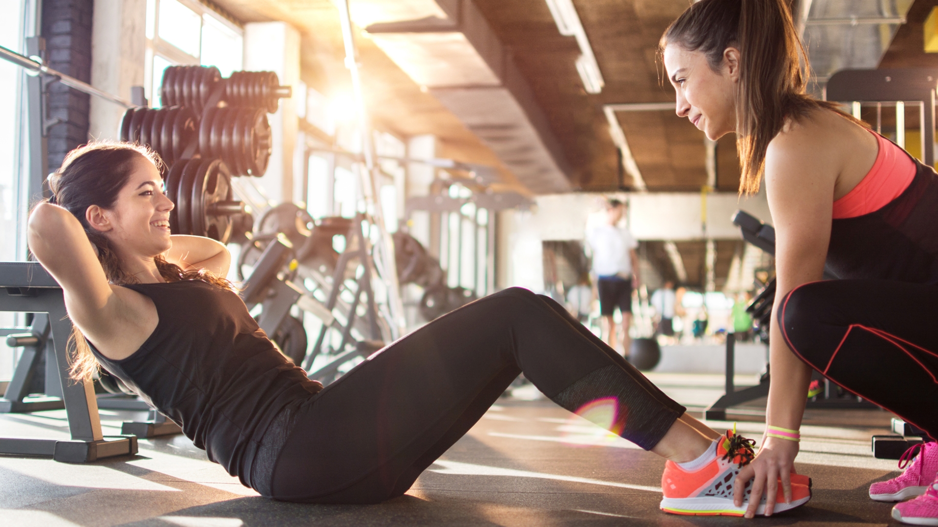 Fitness Instructor assisting a client with sit ups