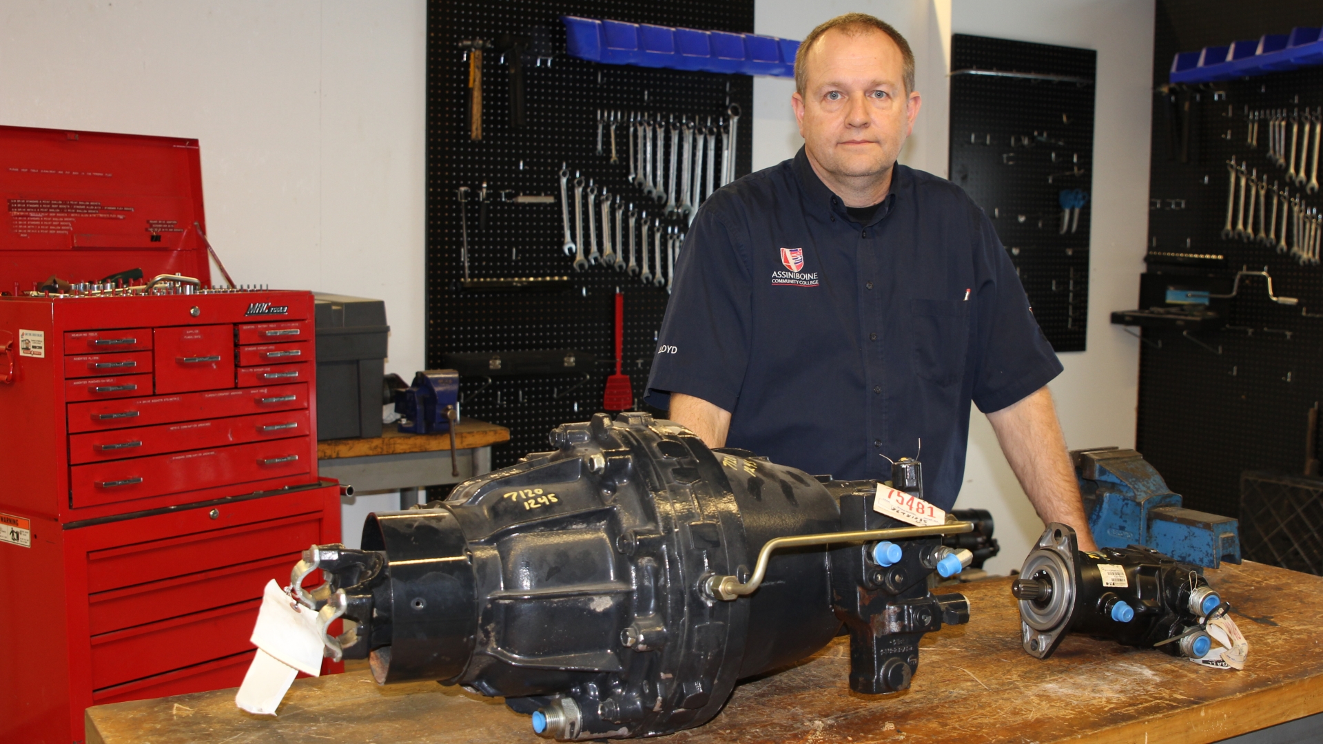 Lloyd Carey stands in his classroom, beside one of his donated items - a Case IH Combine CVT drive unit 