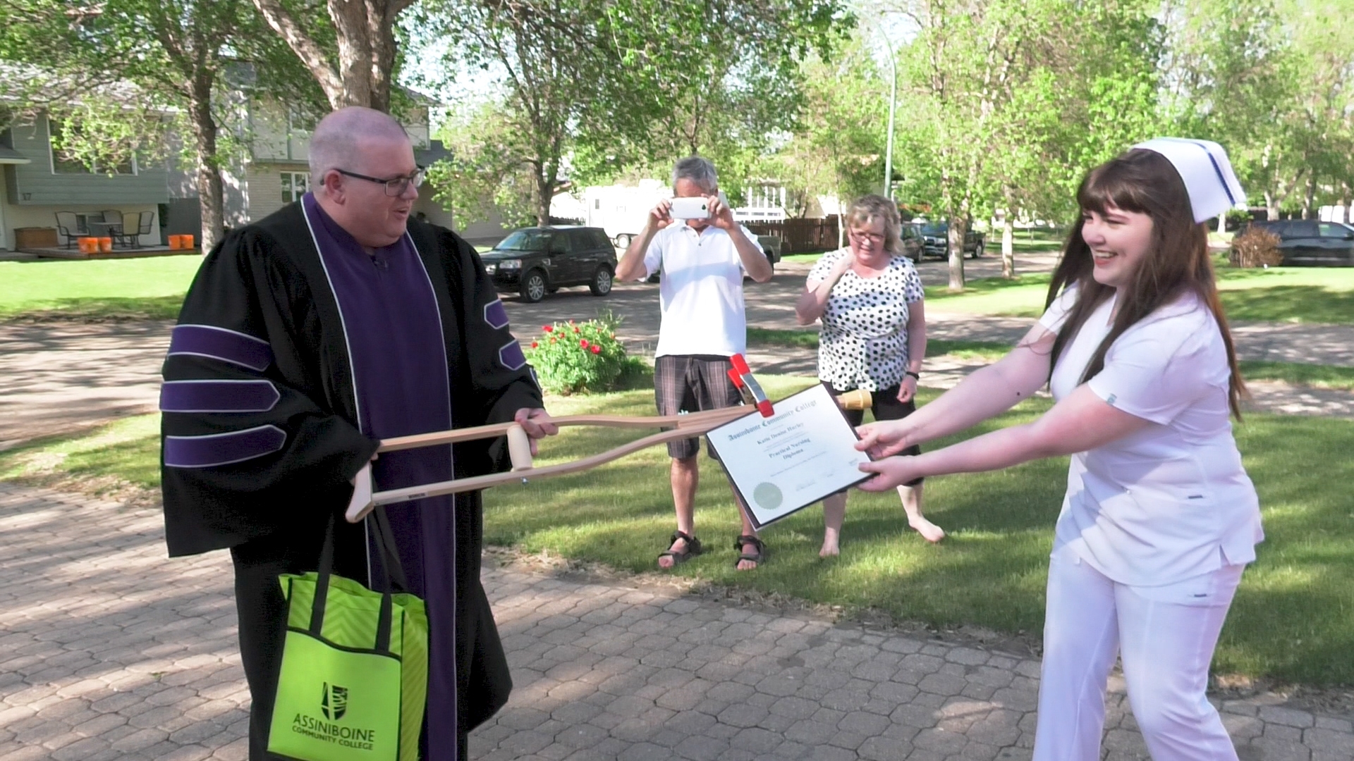 Practical Nursing graduate Katie Hurley receives her diploma from Assiniboine president Mark Frison outside her family home in Brandon.