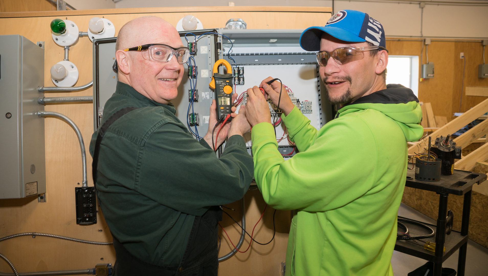 Electrical student and instructor pose while working on wiring. 