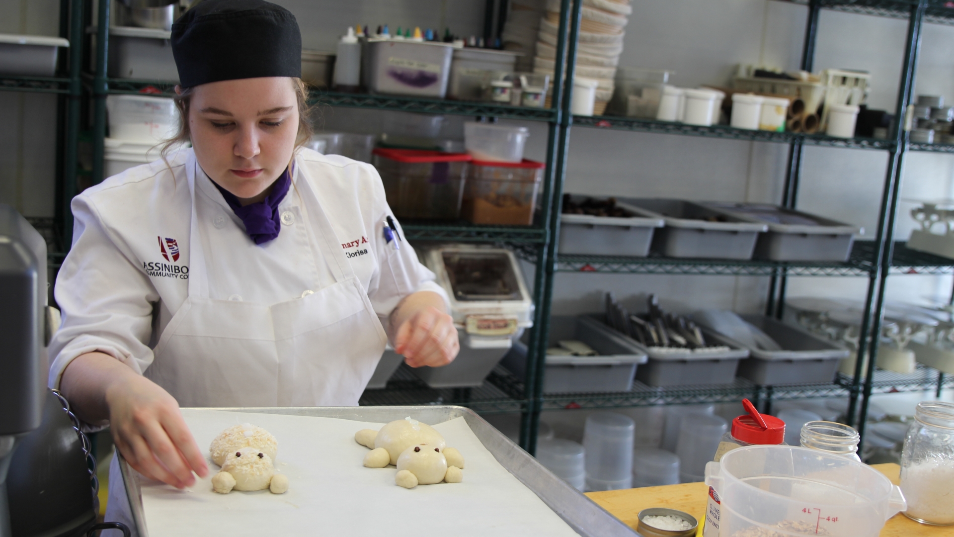 Baking student places dough bears on a baking sheet
