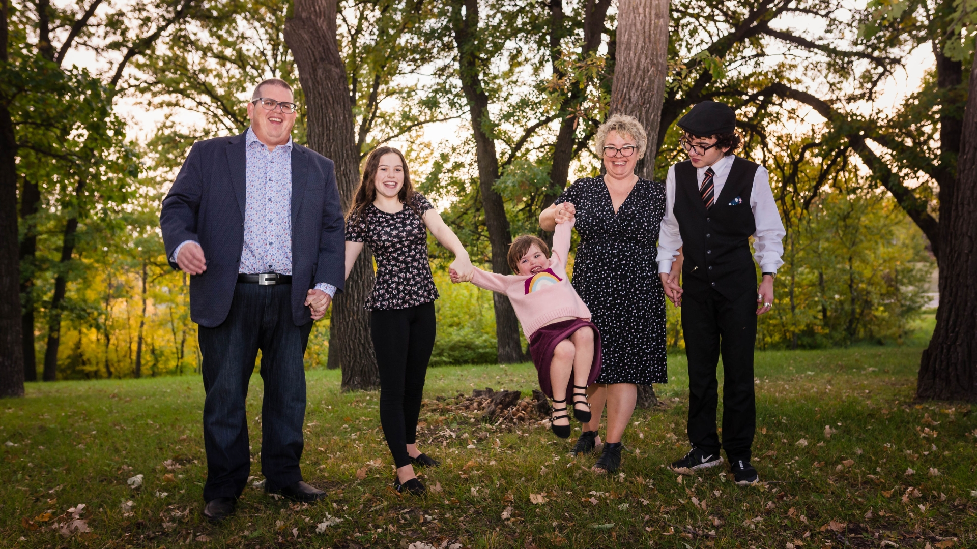 The Frison family, with Mark, Edith and three children, pose among a stand of trees, holding hands