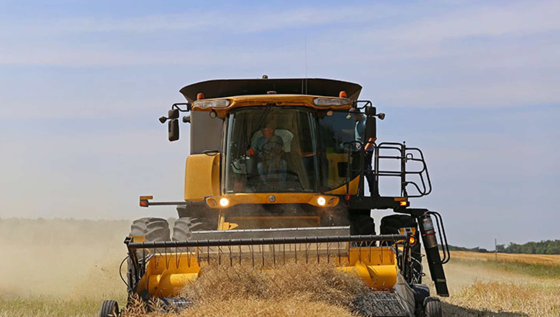 A yellow piece of ag equipment drives through the field toward the camera