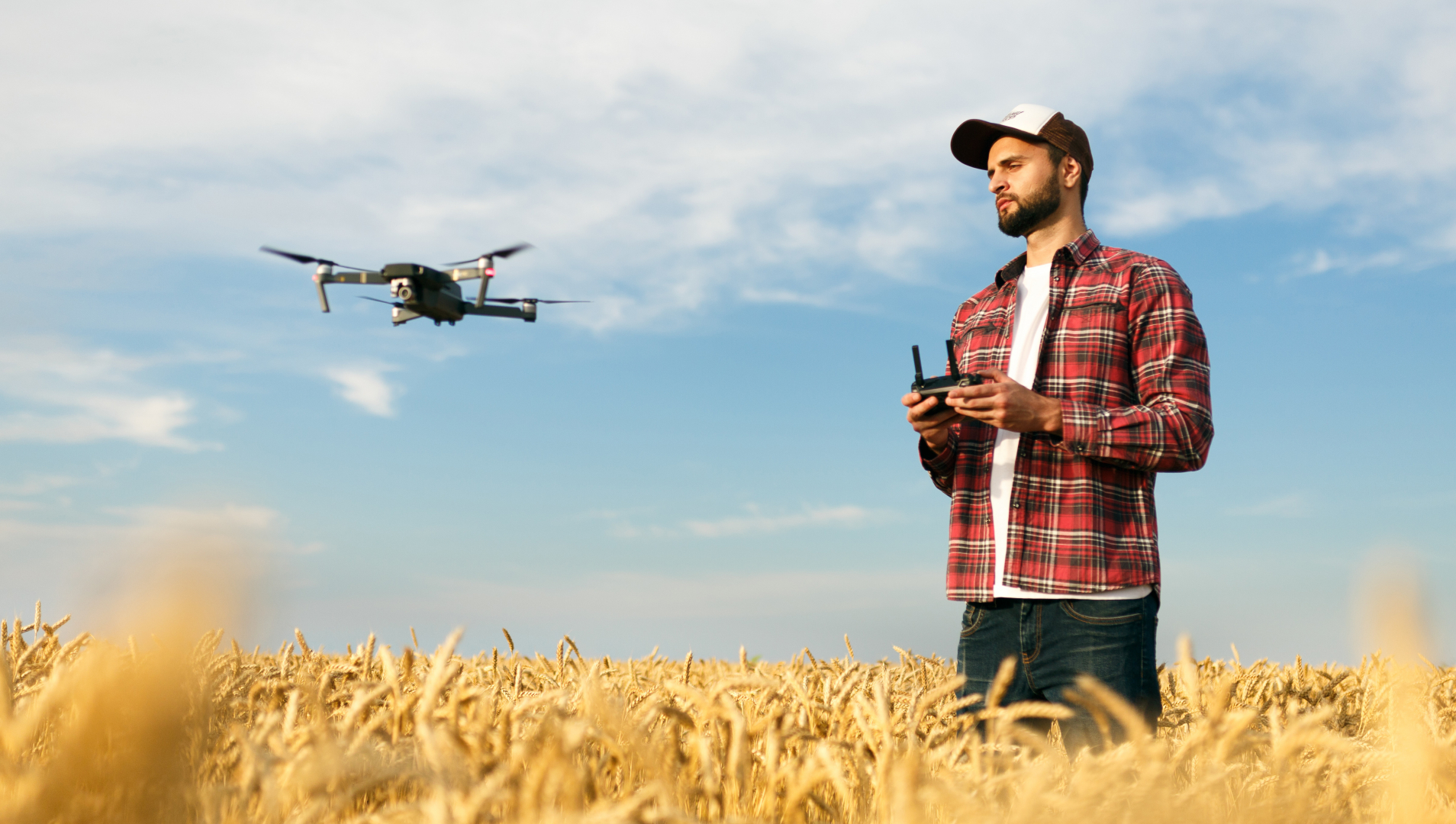 Compact drone hovers in front of farmer with remote controller in his hands.