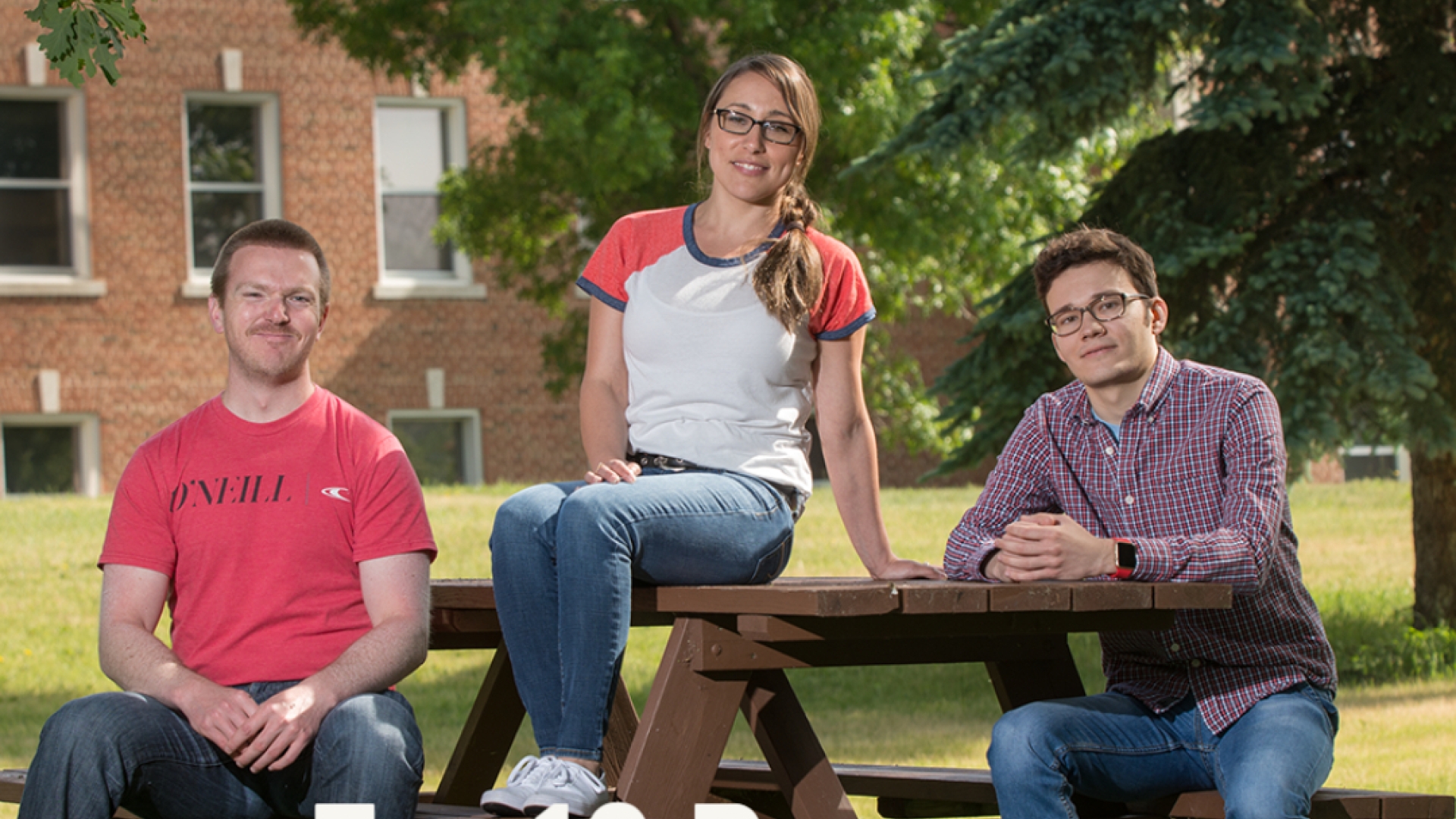 Three students sit at a picnic table, one on the close seat left frame, one atop the table mid-frame and one on the back seat right-frame. The Text "Top 10 Reasons to Donate" is in the lower left frame.
