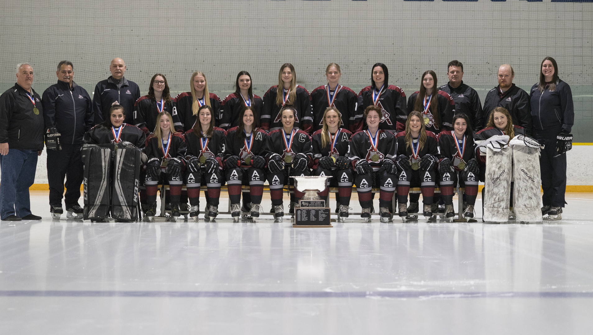 The 2021/22 Cougars Women's Hockey team and coaching staff pose for a team photo with their ACHA National Championship trophy.