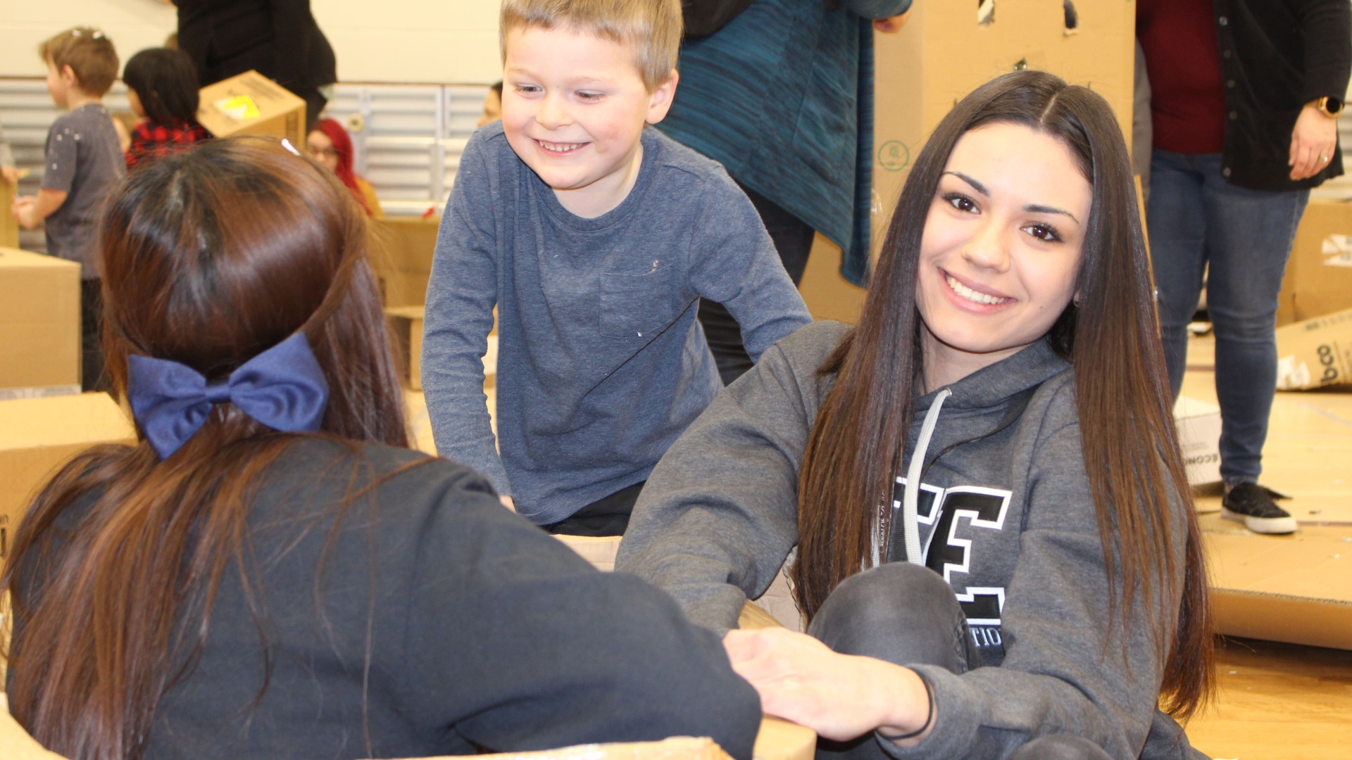 Student playing with kids in cardboard box