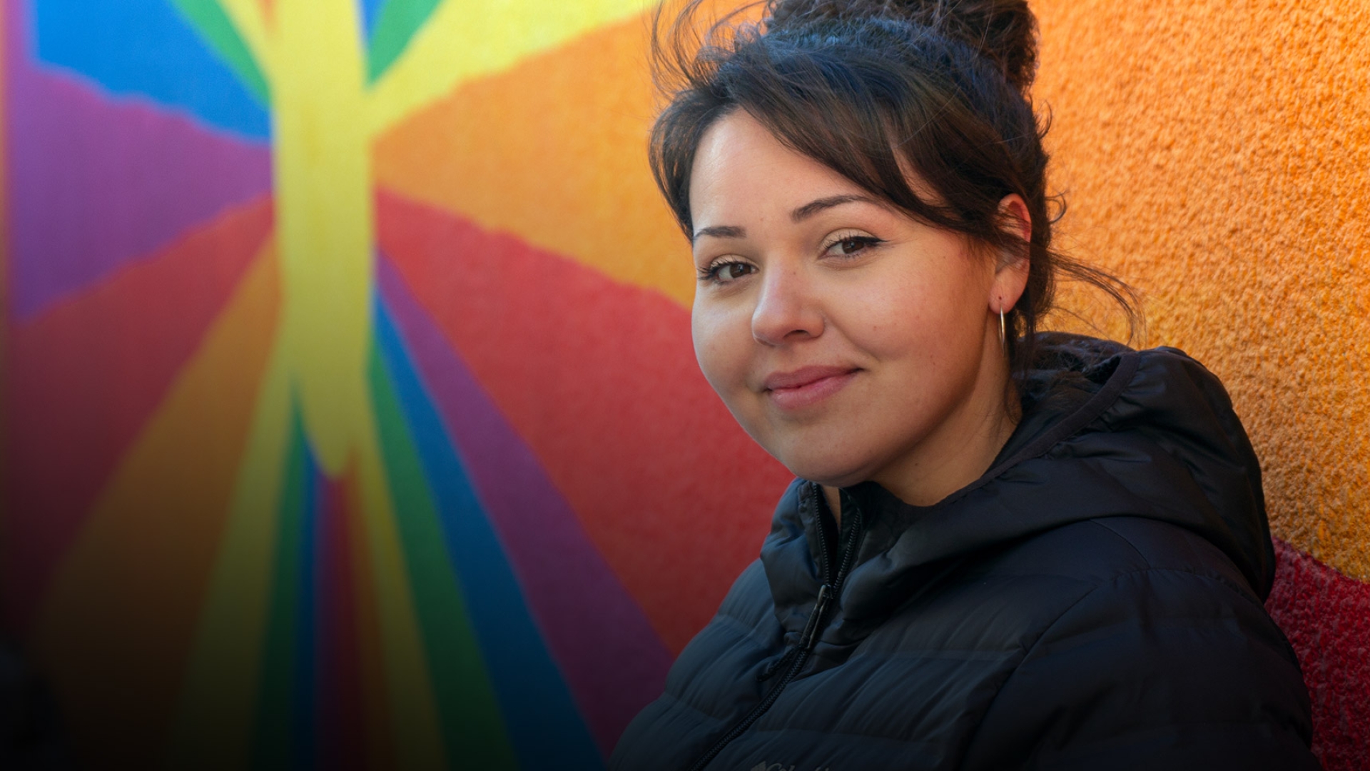 Kristen Paul standing in front of a colourful mural and looking at the camera.