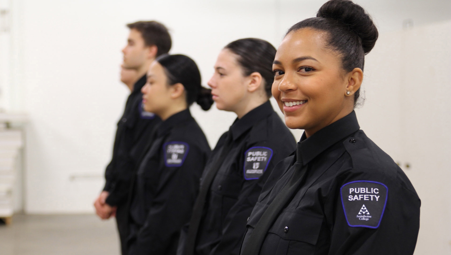 A lineup of Public Safety students in black uniforms, with the closest one smiling at the camera.